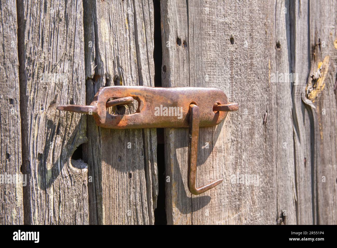 Un vecchio, originale pomolo porta su una secolare porta fienile in legno nel duro pomeriggio sole. Foto Stock