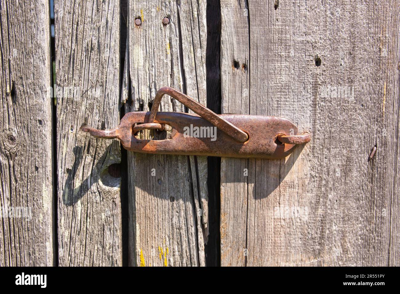 Un vecchio, originale pomolo porta su una secolare porta fienile in legno nel duro pomeriggio sole. Foto Stock