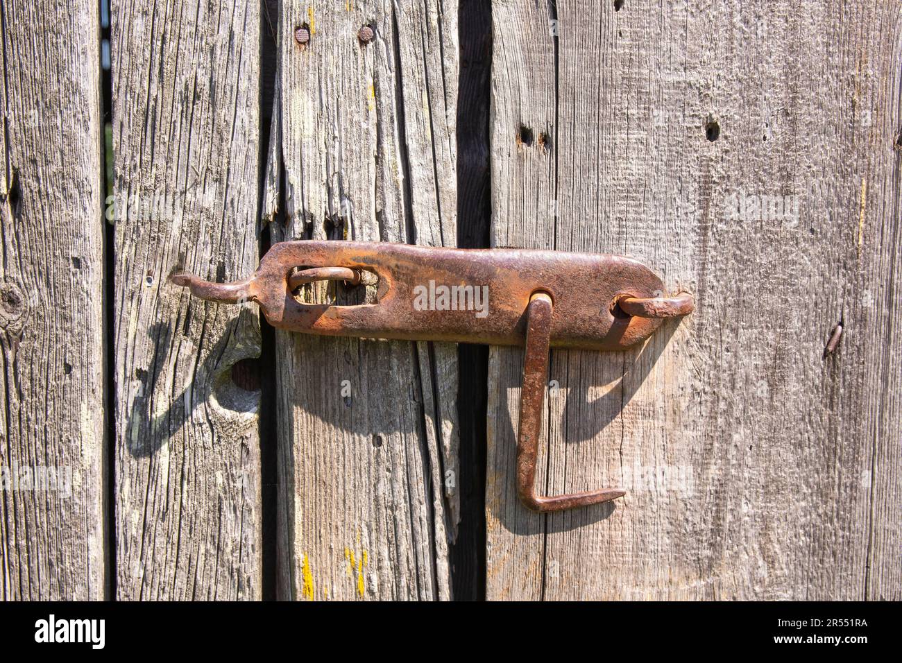 Un vecchio, originale pomolo porta su una secolare porta fienile in legno nel duro pomeriggio sole. Foto Stock