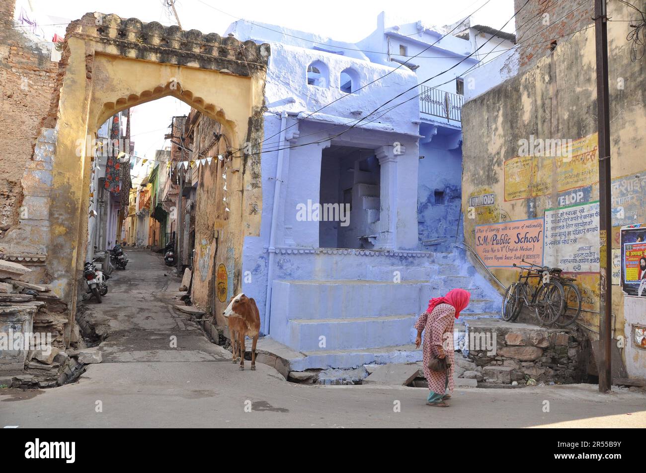 Qualsiasi altra domenica a Bundi, India. Vecchia donna e una mucca che si domandano le strade. Foto Stock