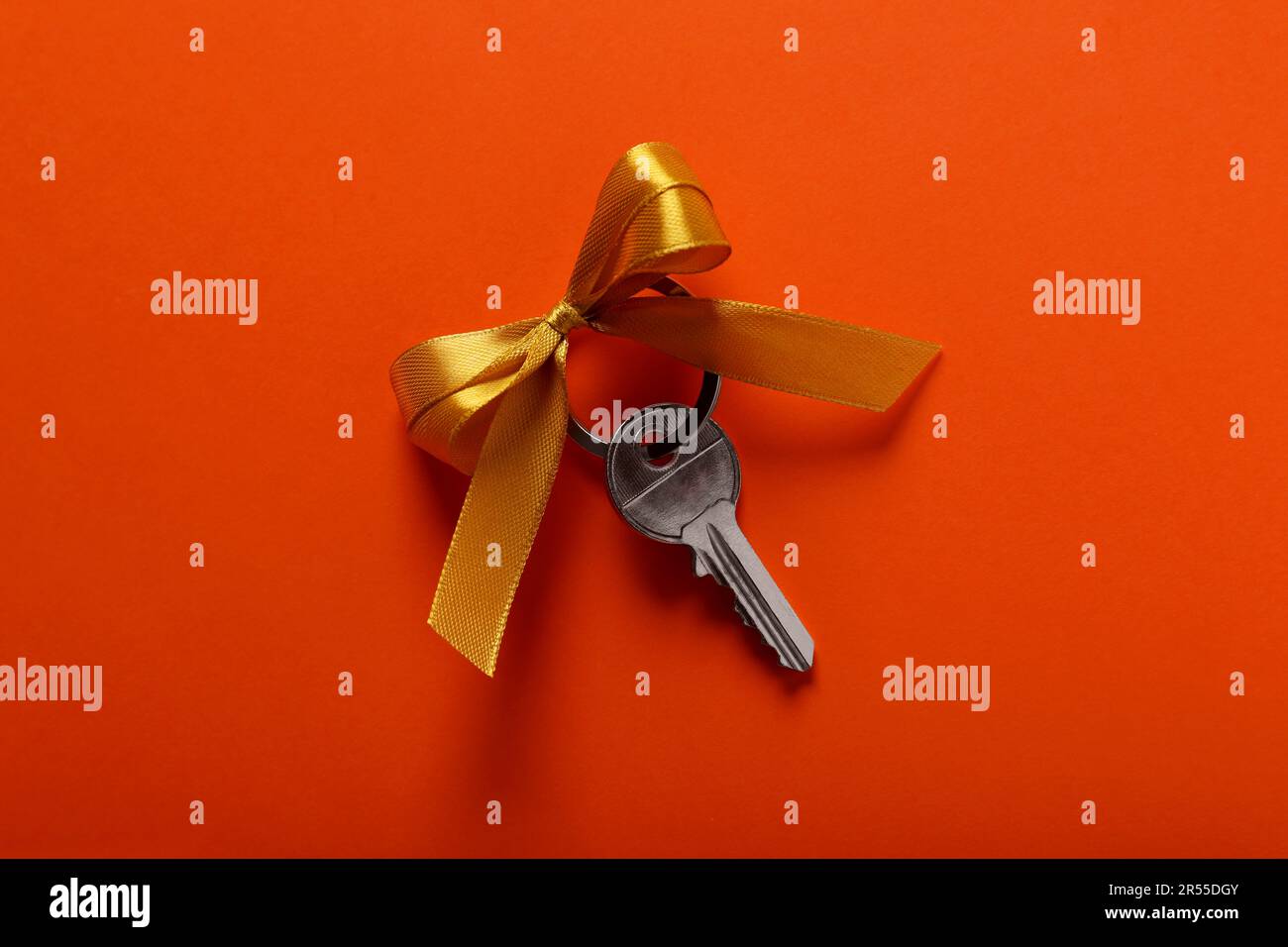 Tasto con arco giallo su sfondo arancione, vista dall'alto. Festa di riscaldamento della casa Foto Stock