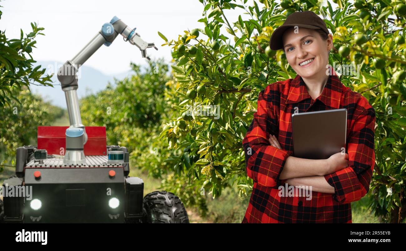 L'agricoltore controlla la trebbiatrice automatica autonoma con il braccio robotico che raccoglie le mele in un'azienda agricola intelligente. Concetto. Foto Stock