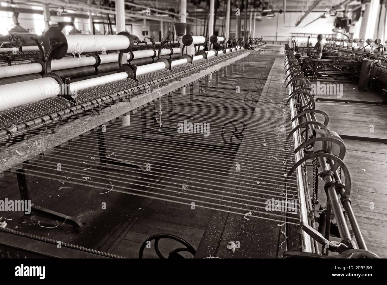 Telaio per filatura ad anello di cotone all'interno di una filatoio del Lancashire, che mostra file di filati che si attorcigliano e avvolgono durante la produzione tessile industriale. Foto Stock
