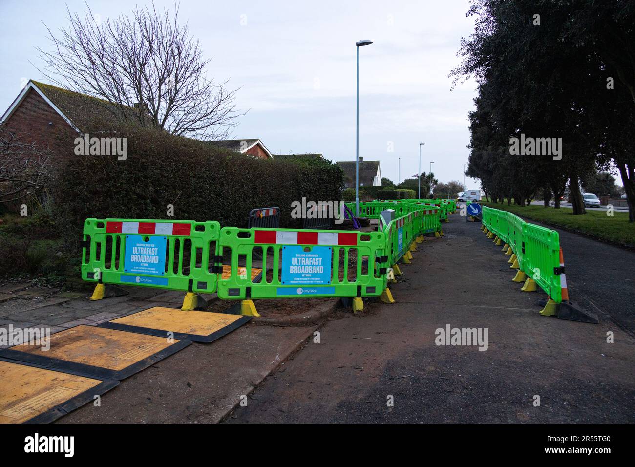 Barriere intorno ai lavori di costruzione sulla pavimentazione durante la posa di nuovi cavi a banda larga ultraveloci a Worthing, Regno Unito Foto Stock