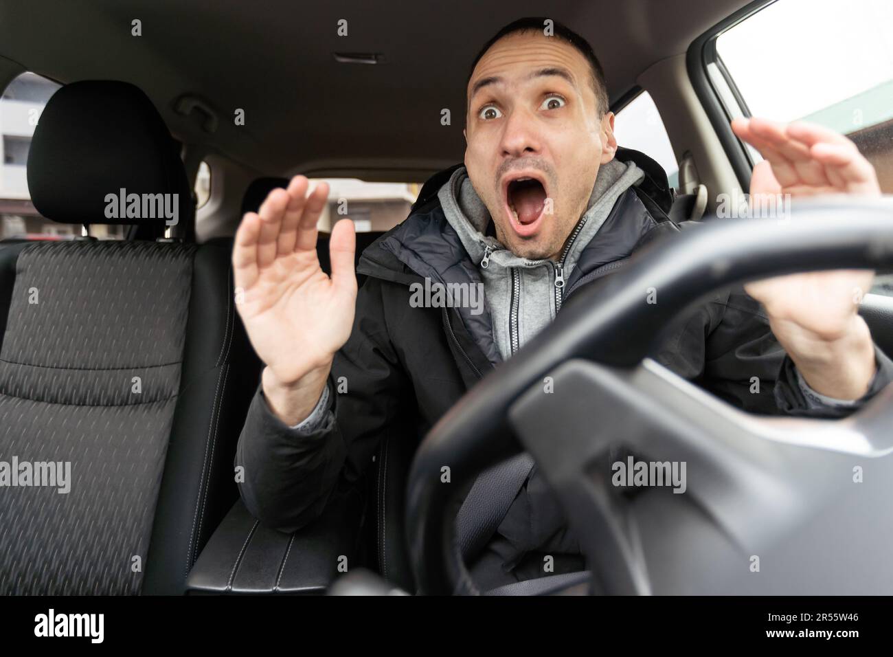 Uomo arrabbiato che guida un'auto. Maschio conducente gesturando e gridando dietro il volante della vettura. Foto Stock