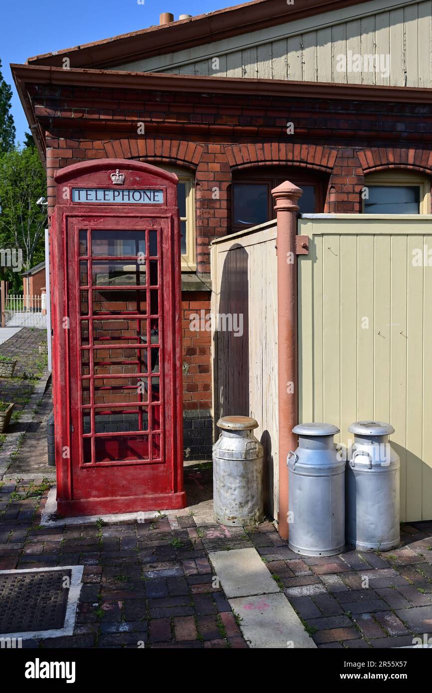 Una cassetta telefonica rossa e baccelli di latte alla stazione di Toddington sulla Gloucestershire Warwickshire Steam Railway. Foto Stock