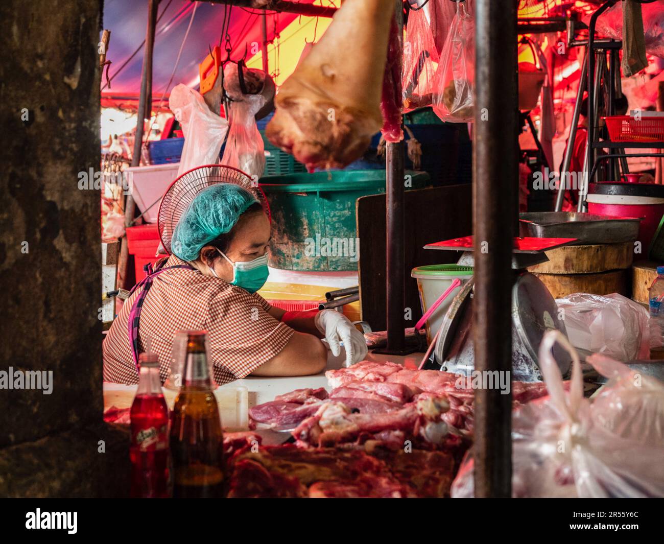 Un macellaio locale presso il suo stand sta guardando il suo smartphone al Khlong Toei Market, il più grande mercato Bangkokís€™aria fresca, sulla Rama IV Road. Foto Stock