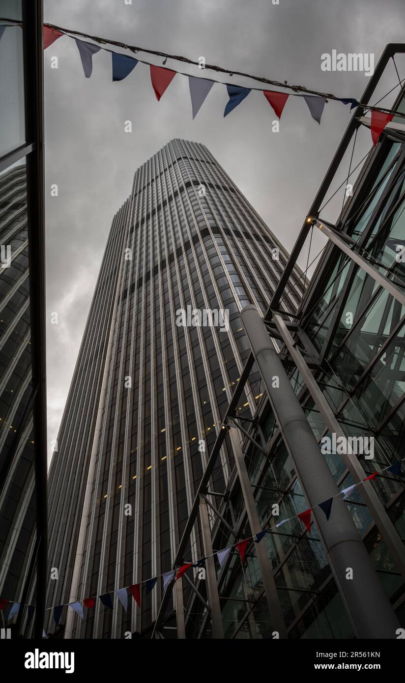 Londra, Regno Unito: Guarda la Torre 42 nella città di Londra con le nuvole scure sopra. Bandiere rosse, bianche e blu volano sopra. Foto Stock