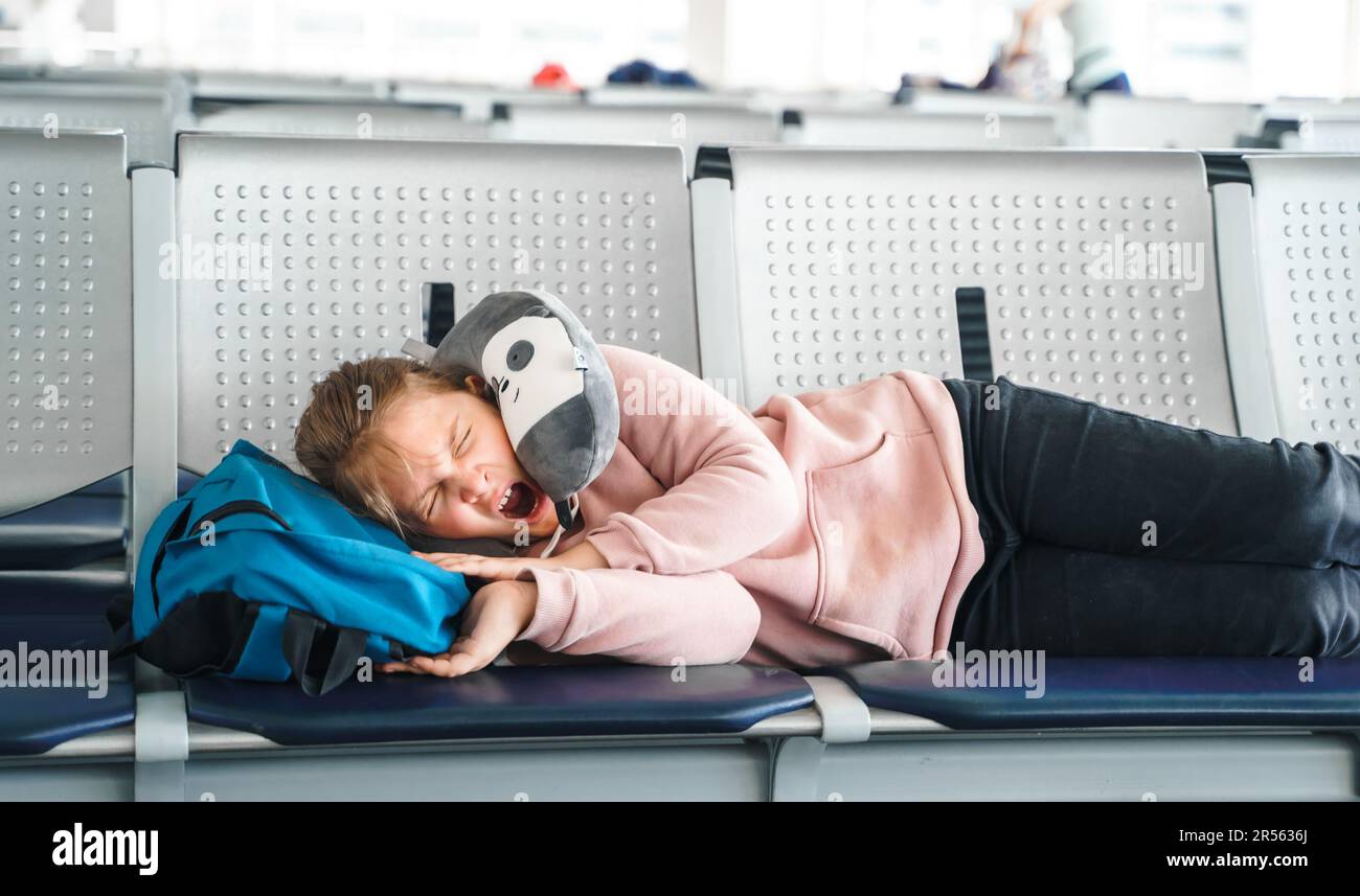 Bambino, ragazzina stanca addormentata, in attesa nella sala di partenza del terminal passeggeri dell'aeroporto con zaino. Seduti sulle sedie in aereo viaggio cuscino. Volo Foto Stock