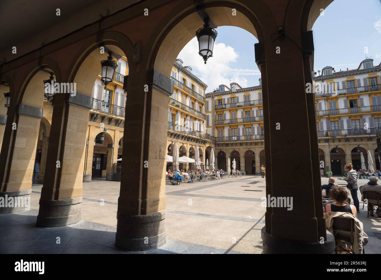 San Sebastian Plaza Constitucion, vista da uno storico colonnato degli appartamenti panoramici all'interno di Plaza de la Constitucion, città vecchia di San Sebastian. Foto Stock