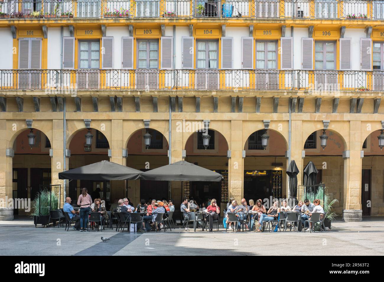 San Sebastian Plaza Constitucion, ammira in estate le persone che si rilassano ai tavoli dei caffè all'interno della Plaza de la Constitucion nella città vecchia di San Sebastian. Foto Stock