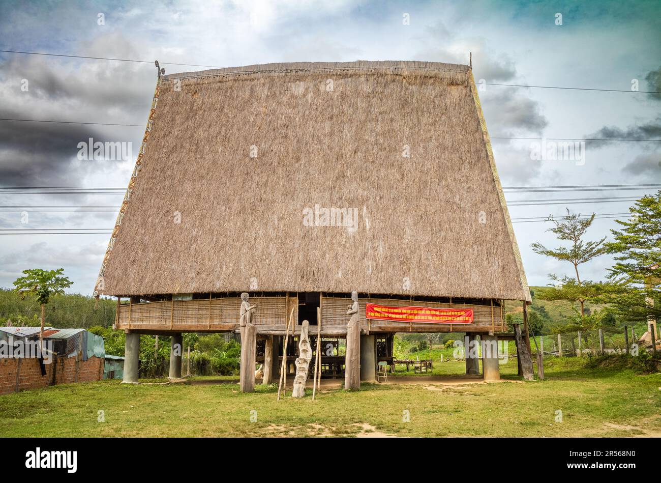 Una tradizionale 'nha rong', o casa culturale, con il suo alto tetto di paglia simile a vela, appartenente alla minoranza etnica Bahnar nel villaggio di Kon Xomluh Foto Stock