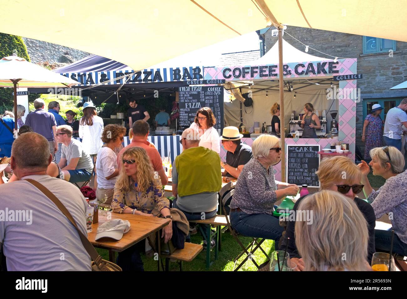 La gente che mangia al bar della torta del caffè e del Pizza Bar al negozio di libro di honesty nel centro della città durante il festival di Hay 2023 Hay-on-Wye Wales UK KATHY DEWITT Foto Stock