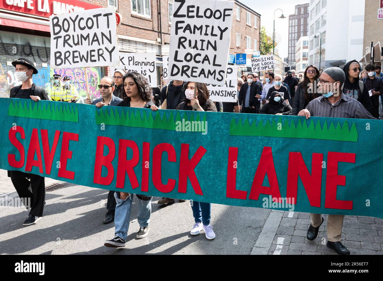 Gli attivisti della comunità marciano dietro un banner "Save Brick Lane" al complesso della fabbrica di birra Truman protestando contro i piani di costruzione di negozi e uffici sul sito. Foto Stock