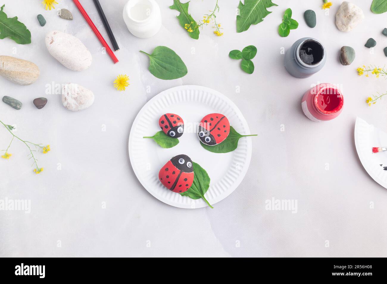 Disegnare una coccinella su una pietra con vernici acriliche. Gli hobby domestici sono autentici. Opere d'arte su pietre. Foto Stock