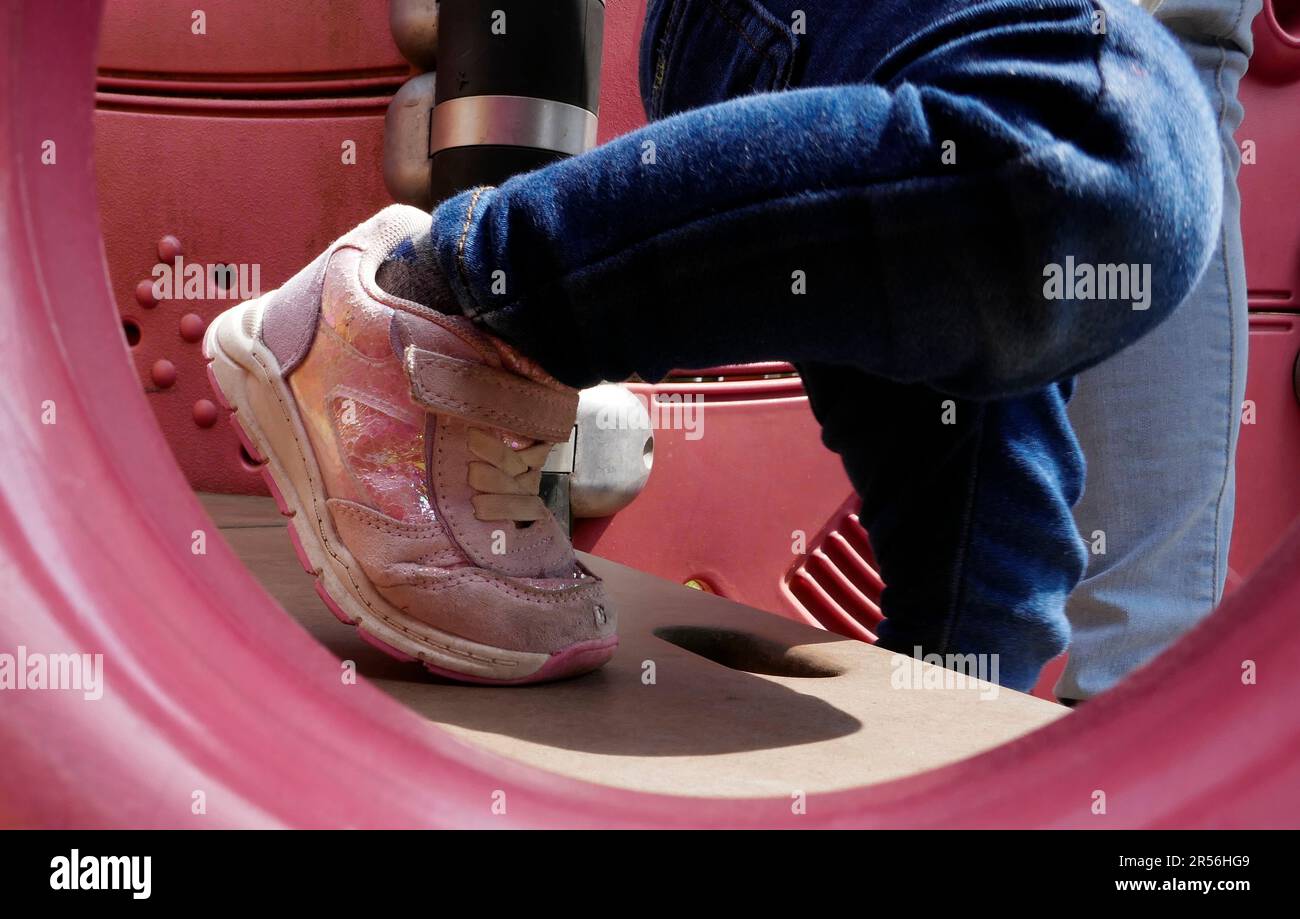 Piedi di una bambina di due anni che scende. Indossa con orgoglio le sneaker rosa alla moda Foto Stock