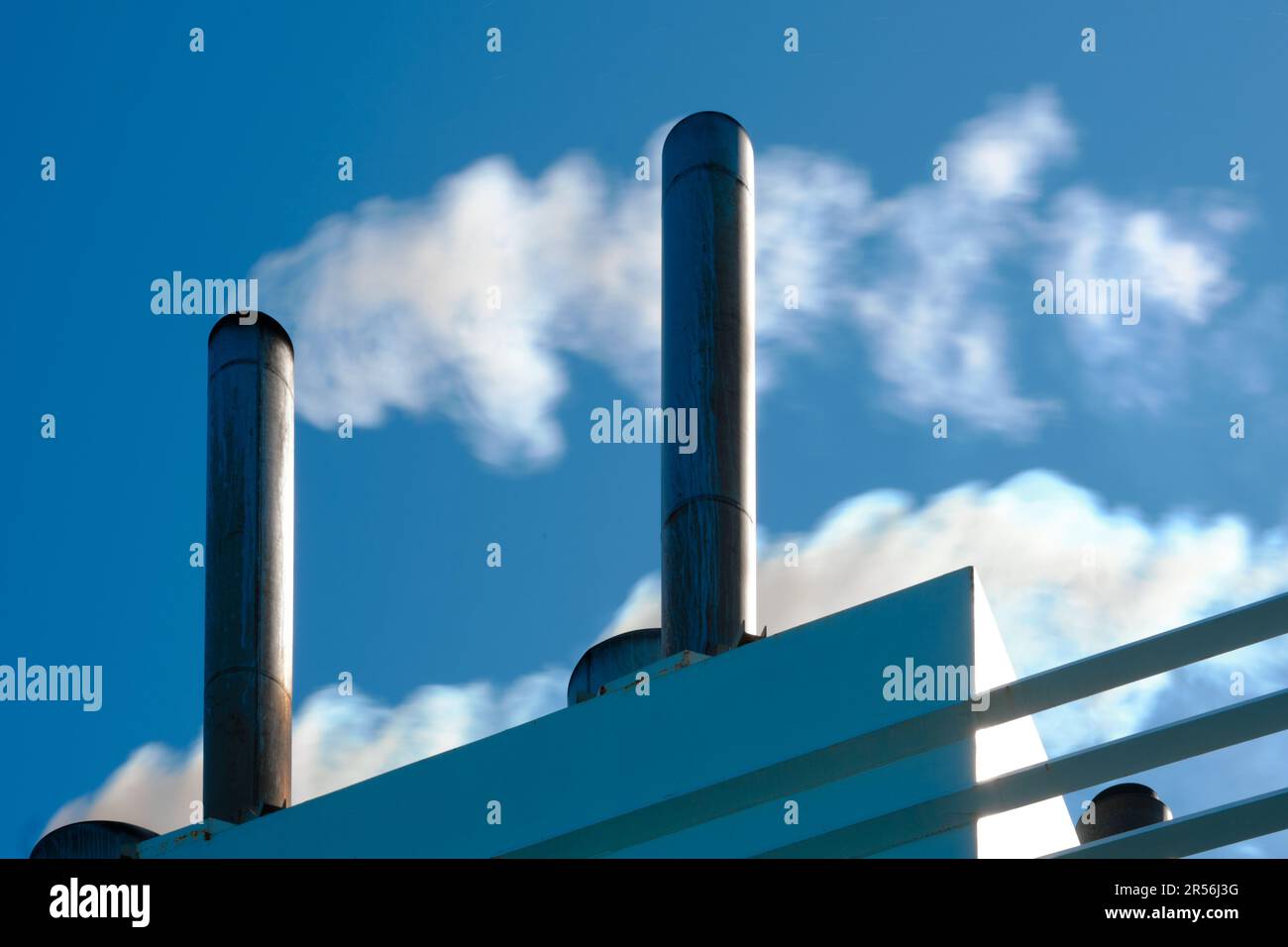Primo piano degli imbuti di un traghetto per passeggeri che emette fumo contro un cielo blu chiaro. Foto Stock