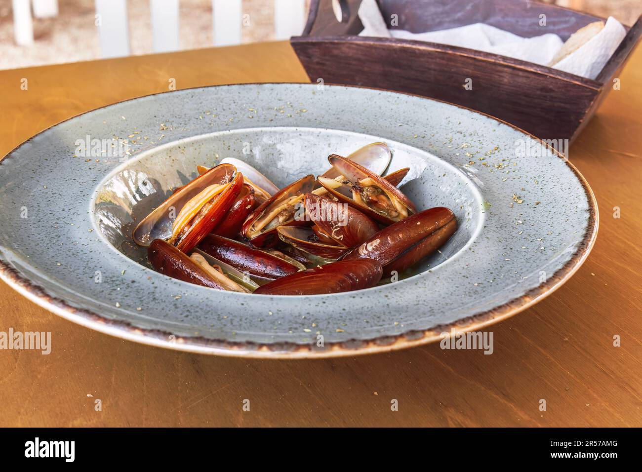 Cozze di conchiglia di Lithofaga cucinate servite su un piatto ad un tavolo di legno. Foto Stock