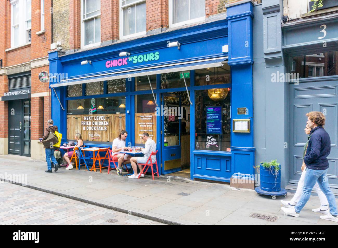 Persone sedute fuori dal ristorante Chick 'n' Sours Chicken and cocktail in Earlham Street, Londra. Foto Stock