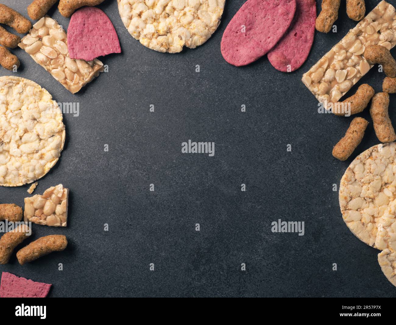 Cracker organici da lenticchie, barbabietole, noci e mais come una cornice su uno sfondo di pietra, spazio per il tuo testo Foto Stock