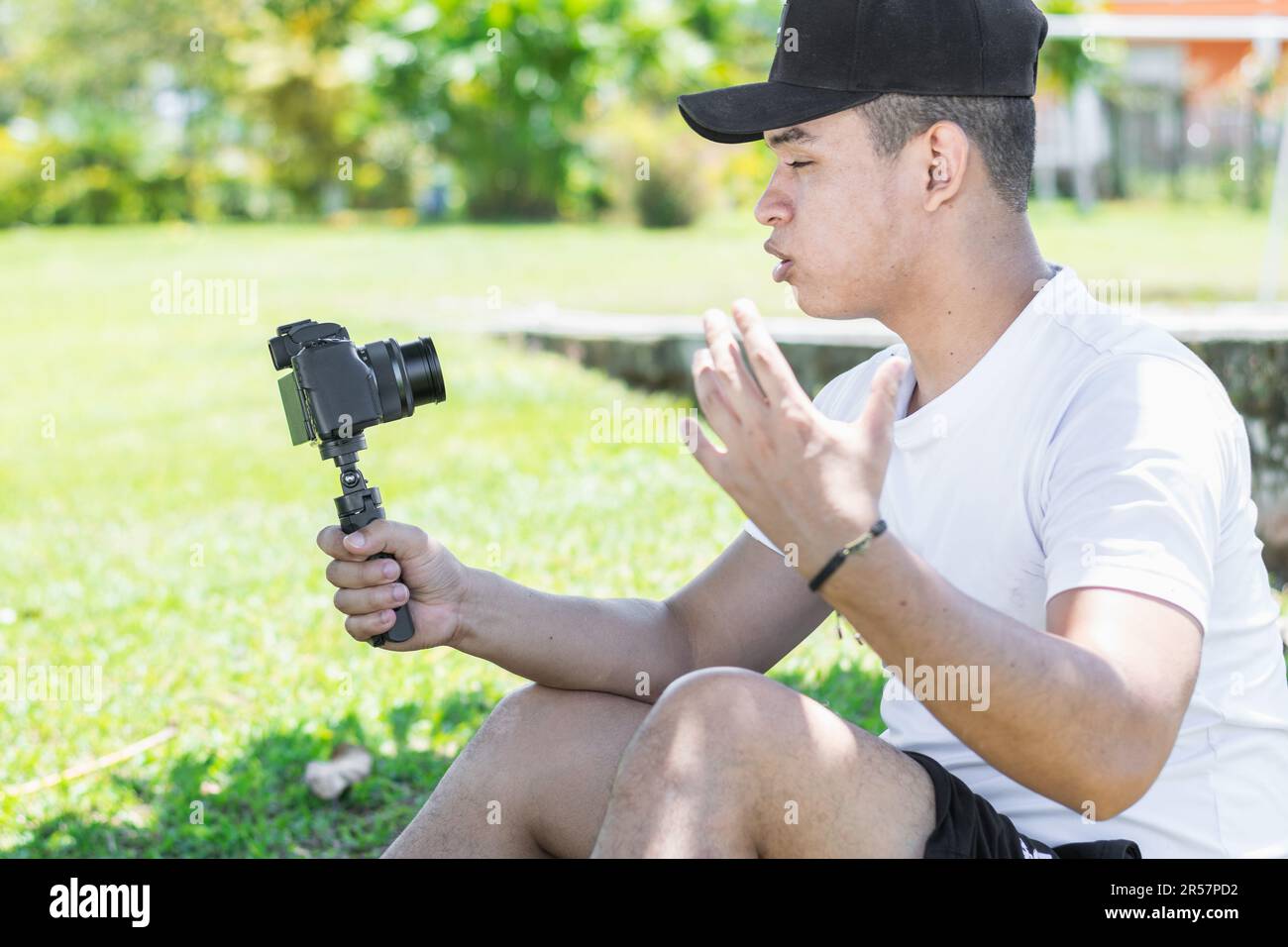 Giovane uomo latino che crea un video vlog, spiegando i progressi del suo viaggio estivo, tenendo la fotocamera con la mano. Foto Stock