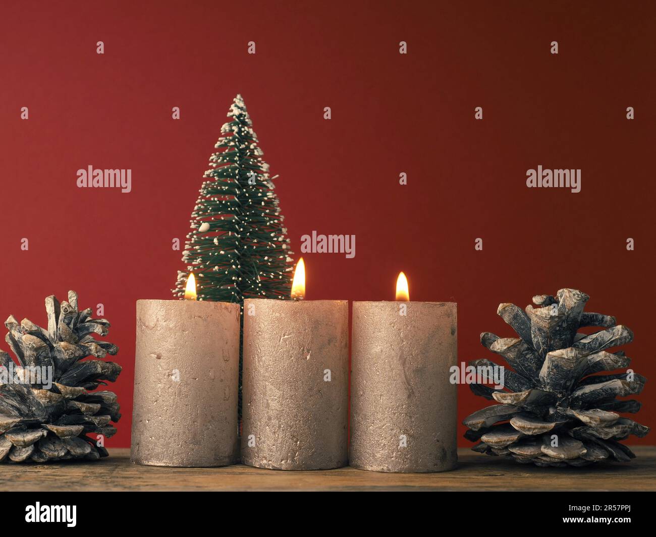 Tre candele dell'Avvento che bruciano su sfondo rosso con decorazione di Natale Foto Stock
