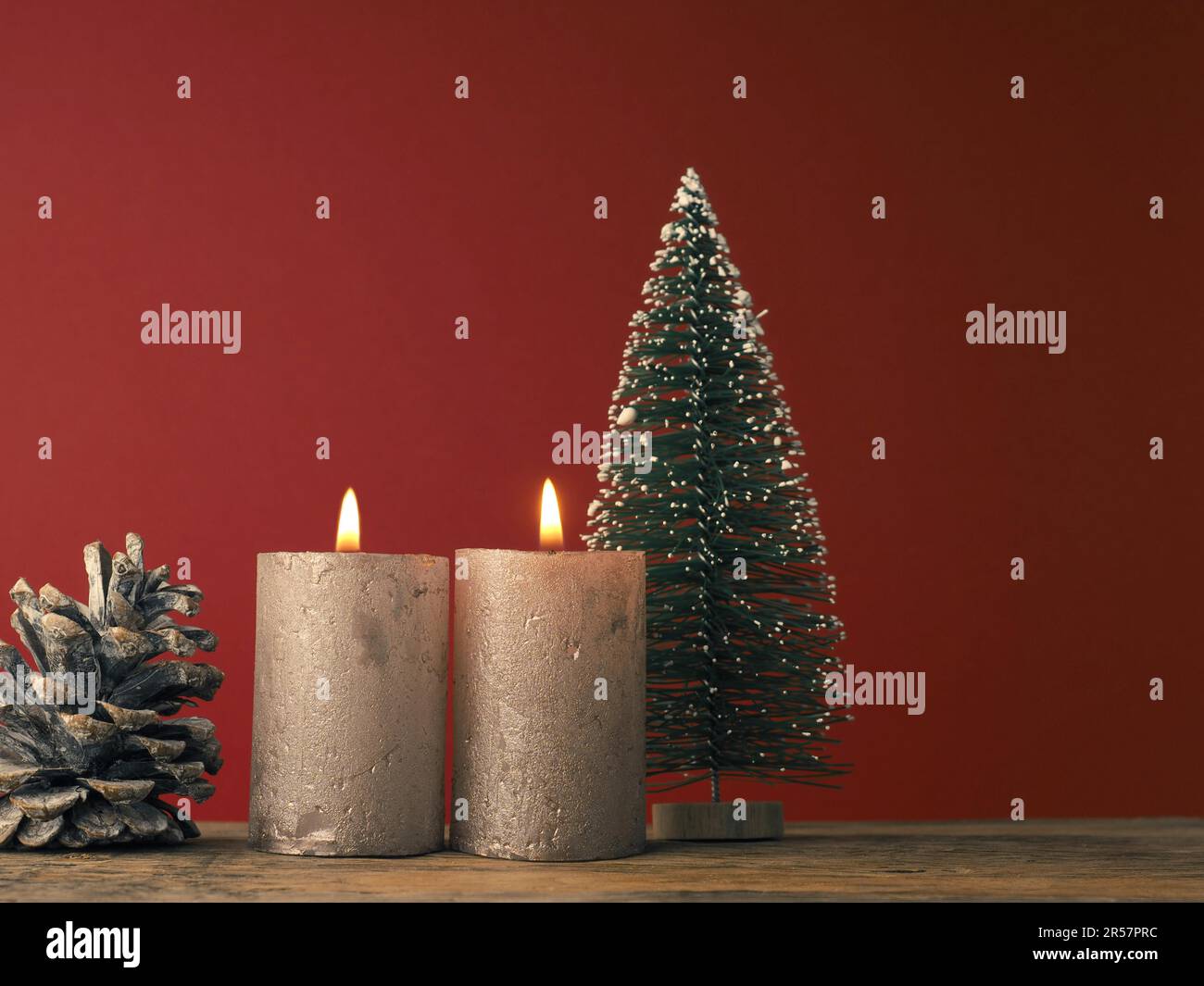 Due candele dell'Avvento che bruciano su sfondo rosso con decorazione di Natale Foto Stock