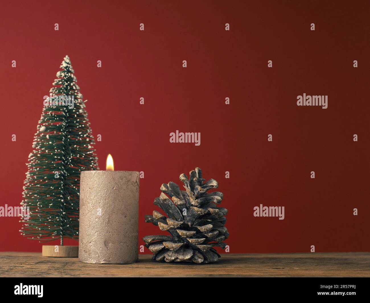 Una candela dell'Avvento su sfondo rosso con decorazione di Natale Foto Stock
