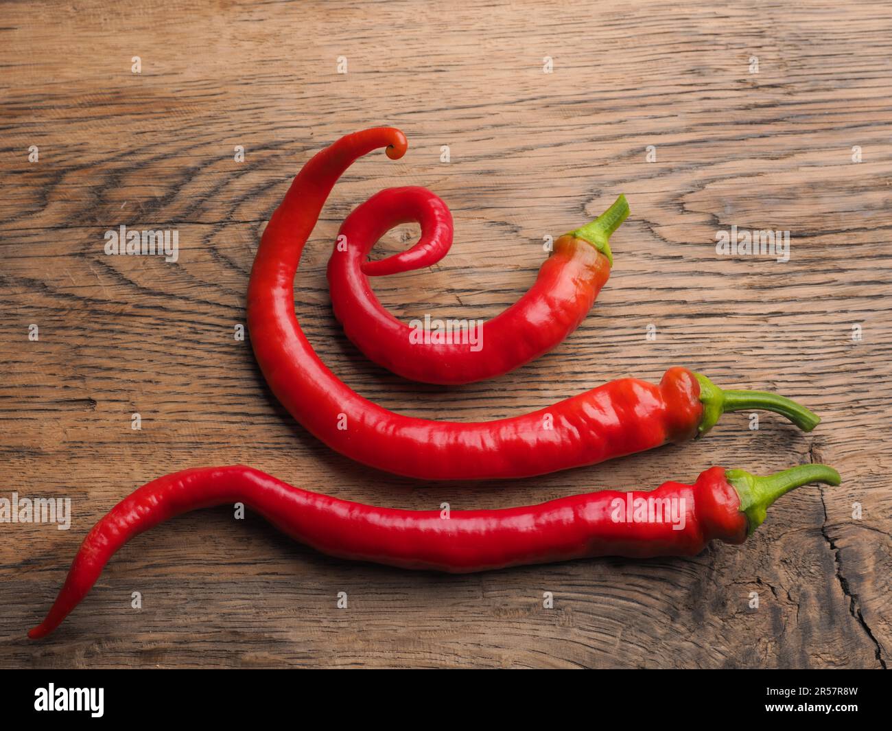 Tre gustosi peperoncini biologici su un tavolo rustico in legno, cibi sani o ingredienti Foto Stock