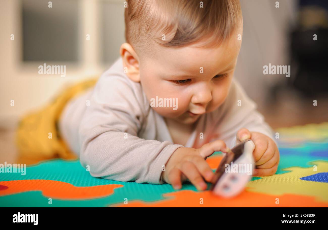 Cute baby boy striscia sul pavimento di casa, esplorare il mondo e le cose intorno a lui. Amore ed emozione familiare Foto Stock