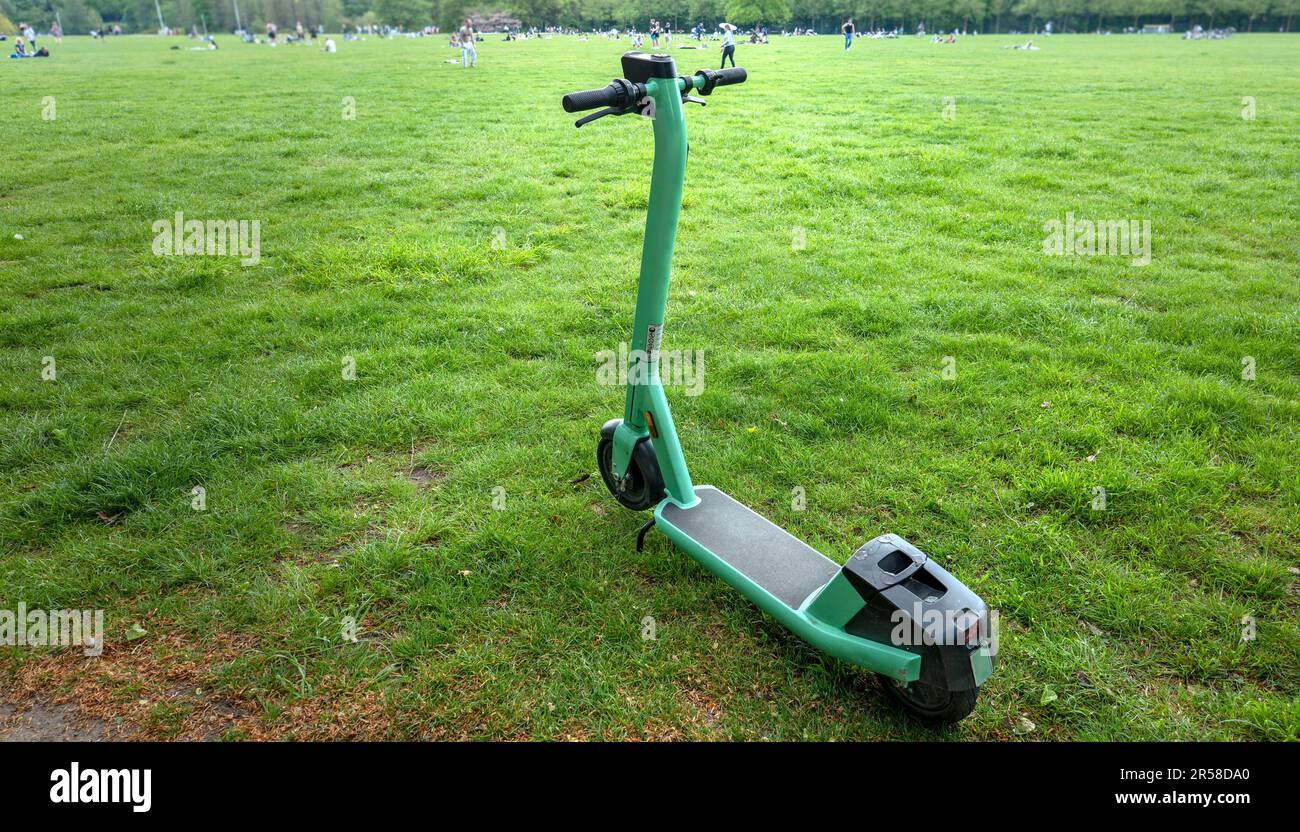 Scooter elettrico verde nel parco, parcheggiato sul prato Foto Stock
