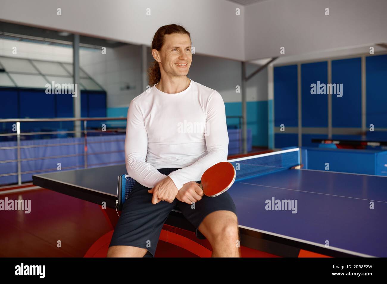 Sportivo soddisfatto che si riposa dopo l'allenamento seduto sul tavolo da tennis Foto Stock