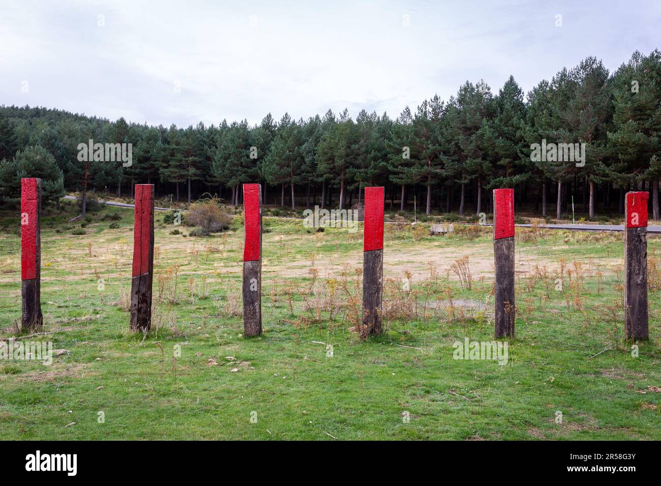 Pali di recinzione in legno con segni rossi contro il bestiame presso il sito di capming Aparcamiento Morcuera II sulla strada M-611 nelle montagne della Sierra de Guadarrama, Spagna. Foto Stock