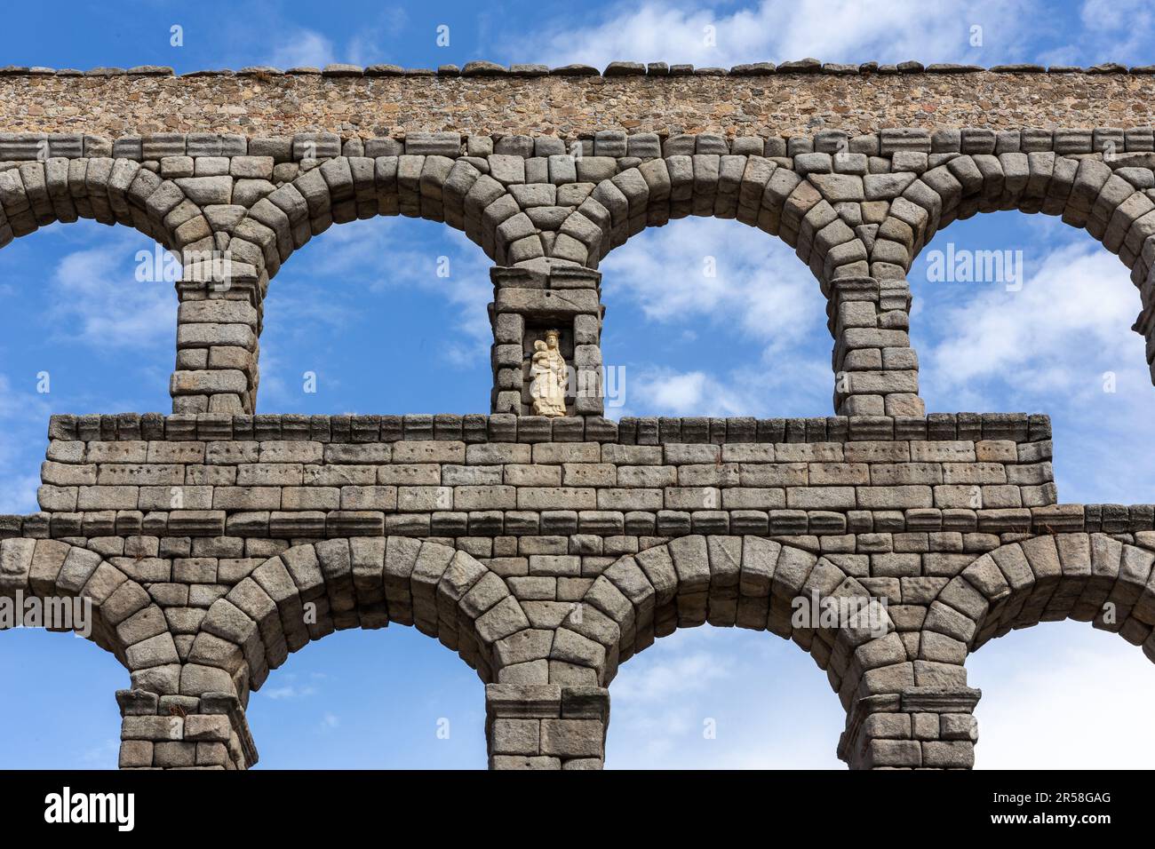 L'Acquedotto di Segovia, Spagna, antica struttura in pietra romana, simbolo di Segovia con nicchia con la Vergine Maria, vista simmetrica contro il cielo blu. Foto Stock