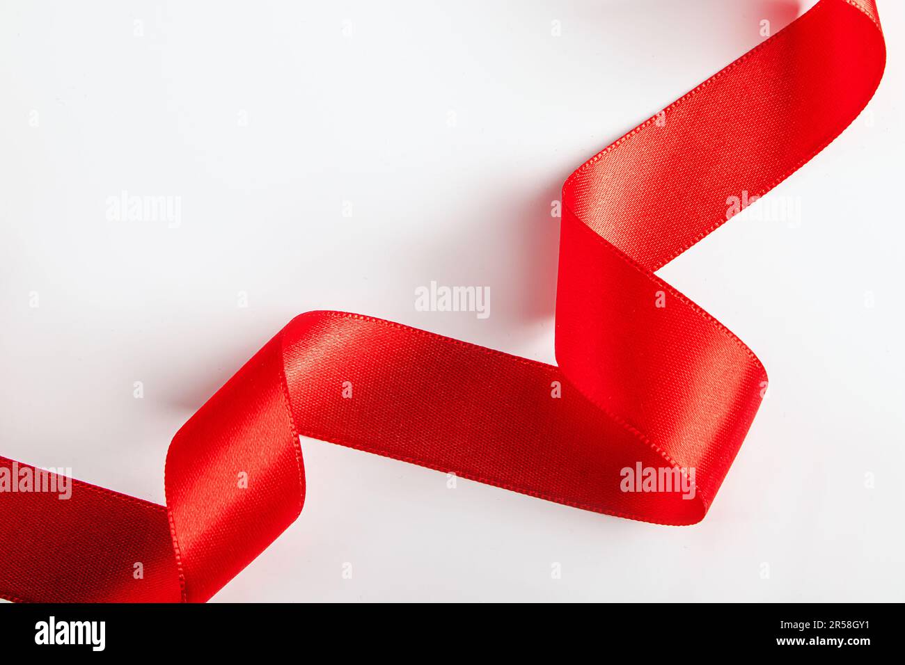 Nastro di seta rossa per l'imballaggio dei regali su sfondo bianco. Ricci di nastro decorativo per le vacanze. Elemento per il design. Foto Stock