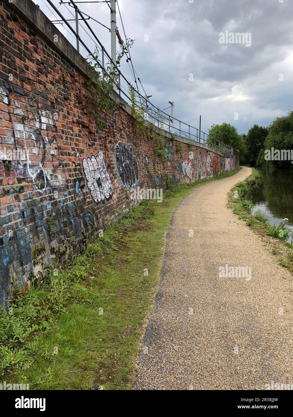 Camminando lungo il Bridgewater Canal a Manchester con le mura urbane in mattoni graffiti Foto Stock