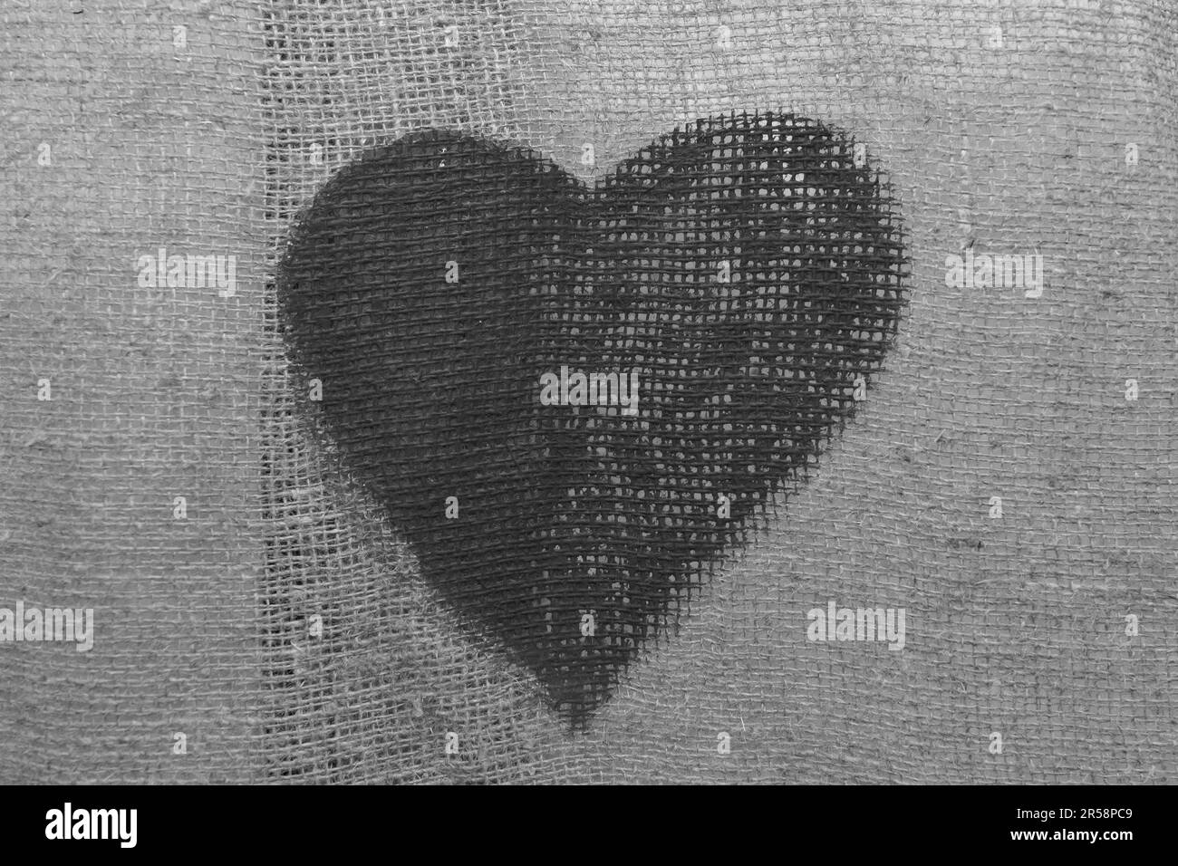 Un cuore grigio scuro è un segno e un simbolo dell'amore deceduto passato su uno sfondo tessuto. Foto Stock