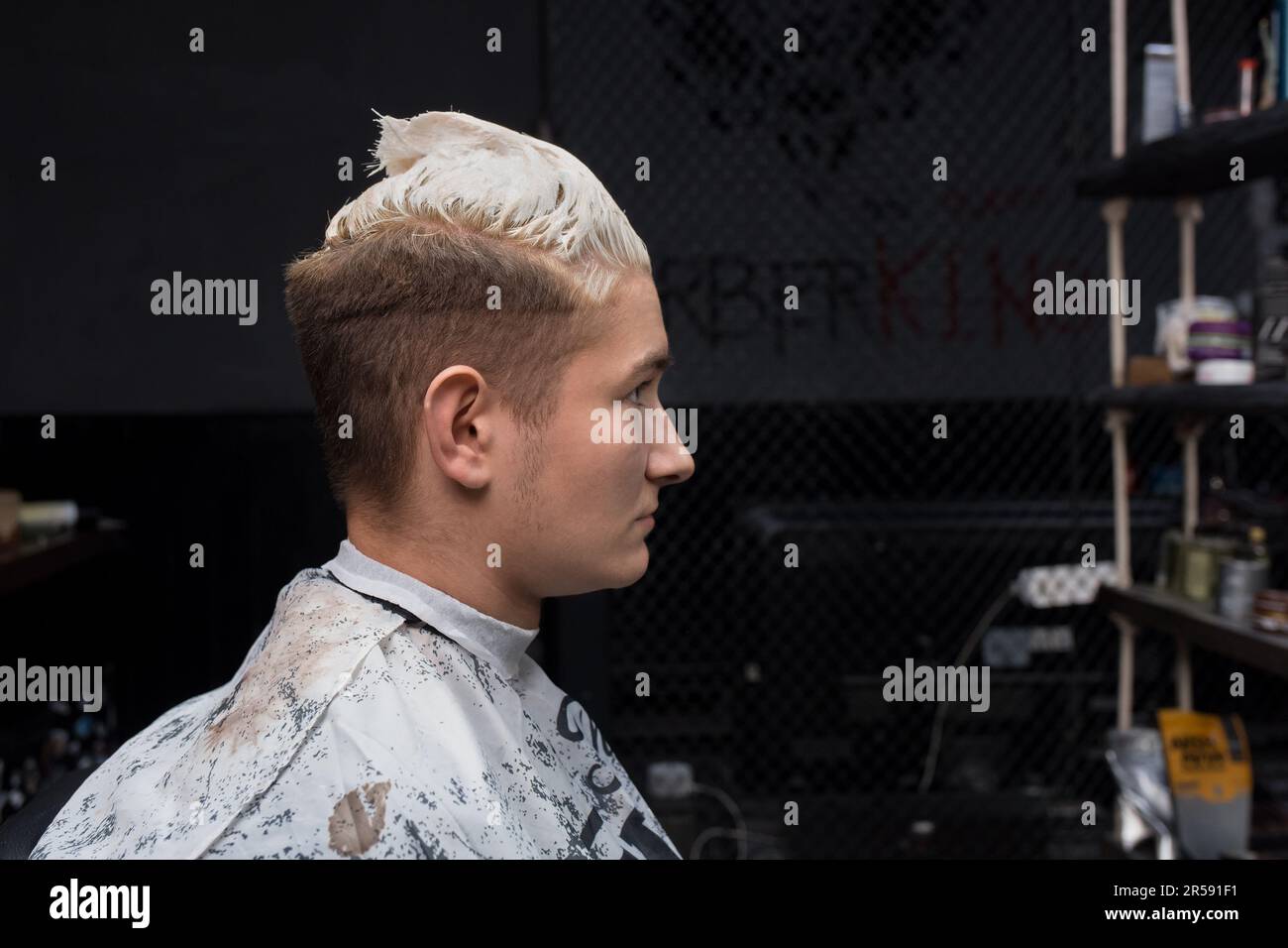 Ritratto in profilo di un cliente barbiere con tintura capelli bianco seduto in un parrucchiere aspetto uomo cura. Foto Stock