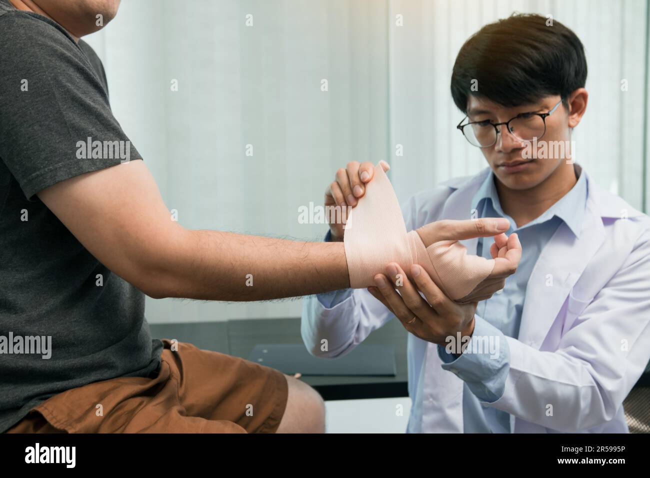 I fisioterapisti asiatici stanno esaminando i risultati della chirurgia del polso dei pazienti. Foto Stock