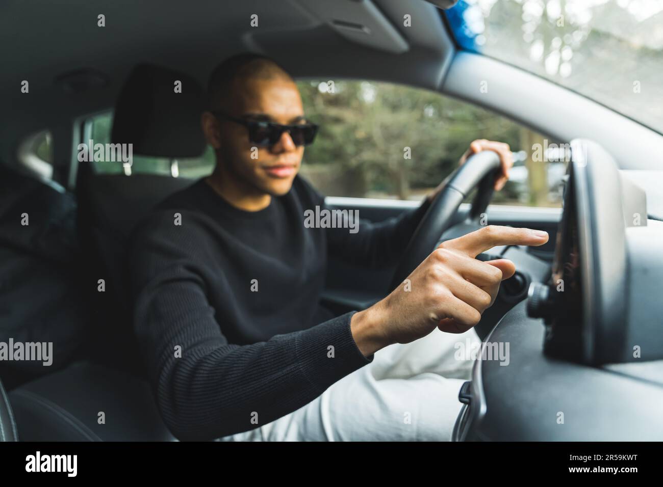 Bel giovane uomo nero che utilizza uno schermo a sfioramento del sistema di navigazione GPS in auto. Foto di alta qualità Foto Stock