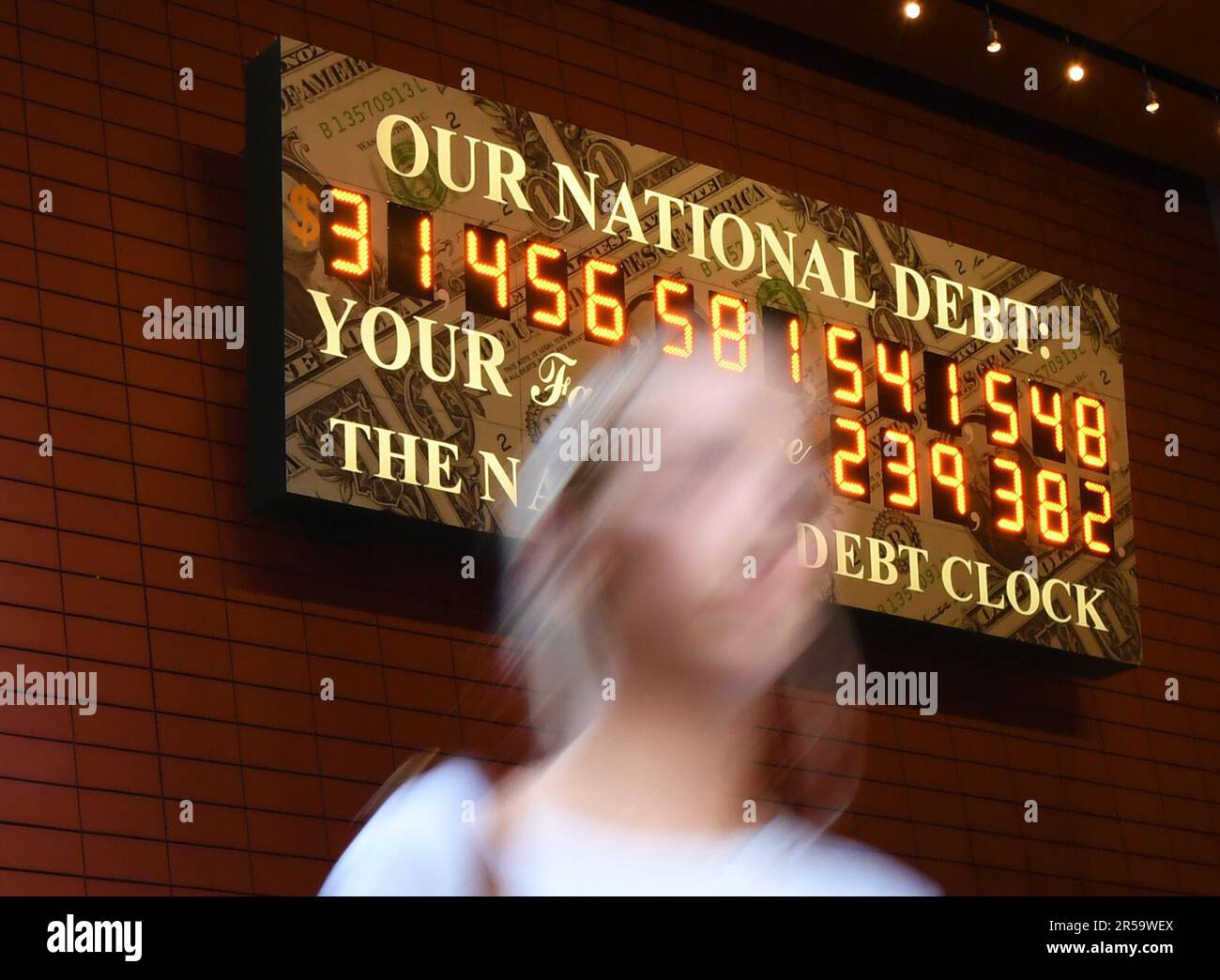 New York, Stati Uniti. 1st giugno, 2023. Una donna passa davanti al National Debt Clock a New York, negli Stati Uniti, il 1 giugno 2023. Dopo mesi di lotta di braccio partisan, gli Stati Uniti Il Congresso ha approvato il disegno di legge per aumentare il tetto del debito americano dopo il passaggio del Senato alla fine di giovedì, la 103rd volta dal 1945, consentendo al governo di evitare un default del debito prendendo a prestito di più. Credit: Li Rui/Xinhua/Alamy Live News Foto Stock