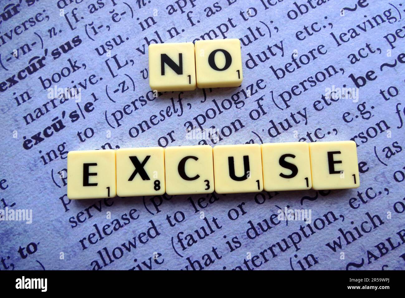 "Non ci sono scuse" scritto utilizzando tessere di lettere in stile Scrabble poste su una pagina di dizionario aperta, che rappresenta motivazione, responsabilità e risposta personale Foto Stock