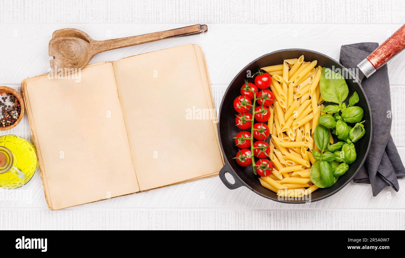 Una vivace rappresentazione della bandiera italiana fatta con pasta, basilico e pomodori, splendidamente presentata in una padella, e una pagina di libro di cucina per il vostro r Foto Stock