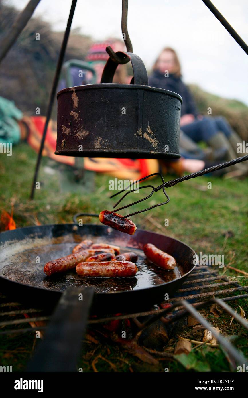 Una famiglia grigliate salsicce e bolle d'acqua su un fuoco da campo vicino Ellingstring, North Yorkshire, Inghilterra, Regno Unito, il 22 2009 marzo. Foto Stock