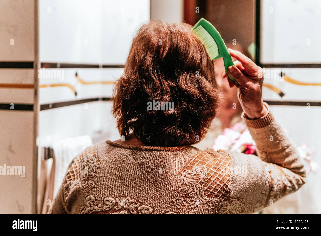 vecchia donna che pettina i capelli davanti allo specchio Foto Stock