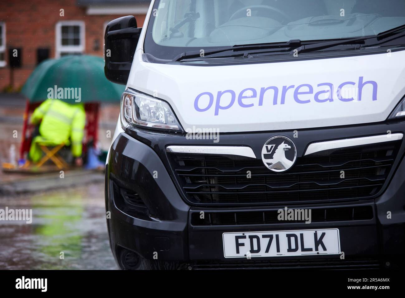 Wet Weather BT OpenReach engineer che collega la banda larga ad alta velocità che lavora sotto la pioggia Foto Stock