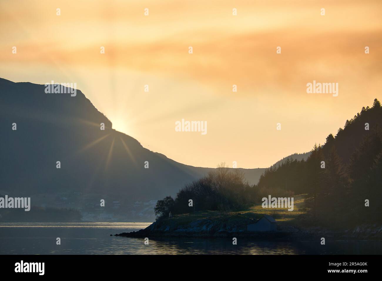 Fiordo con vista delle montagne e del paesaggio fiordo in Norvegia. Il sole si trova dietro la montagna. Paesaggio girato dal nord della Scandinavia Foto Stock