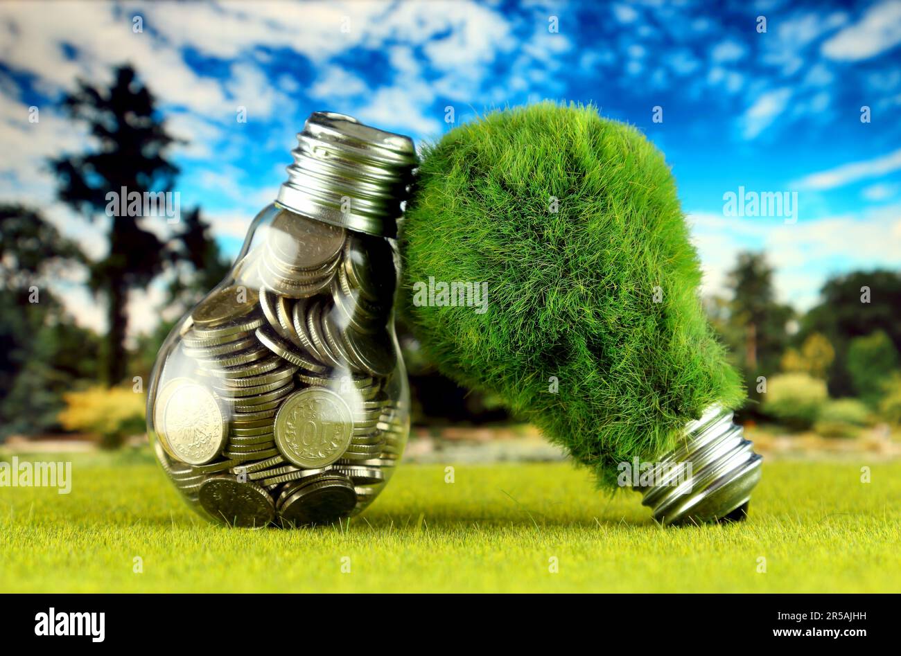 Monete all'interno della lampadina e lampadina verde eco con erba. Concetto di energia rinnovabile. I prezzi dell'elettricità, il risparmio energetico in famiglia. Foto Stock