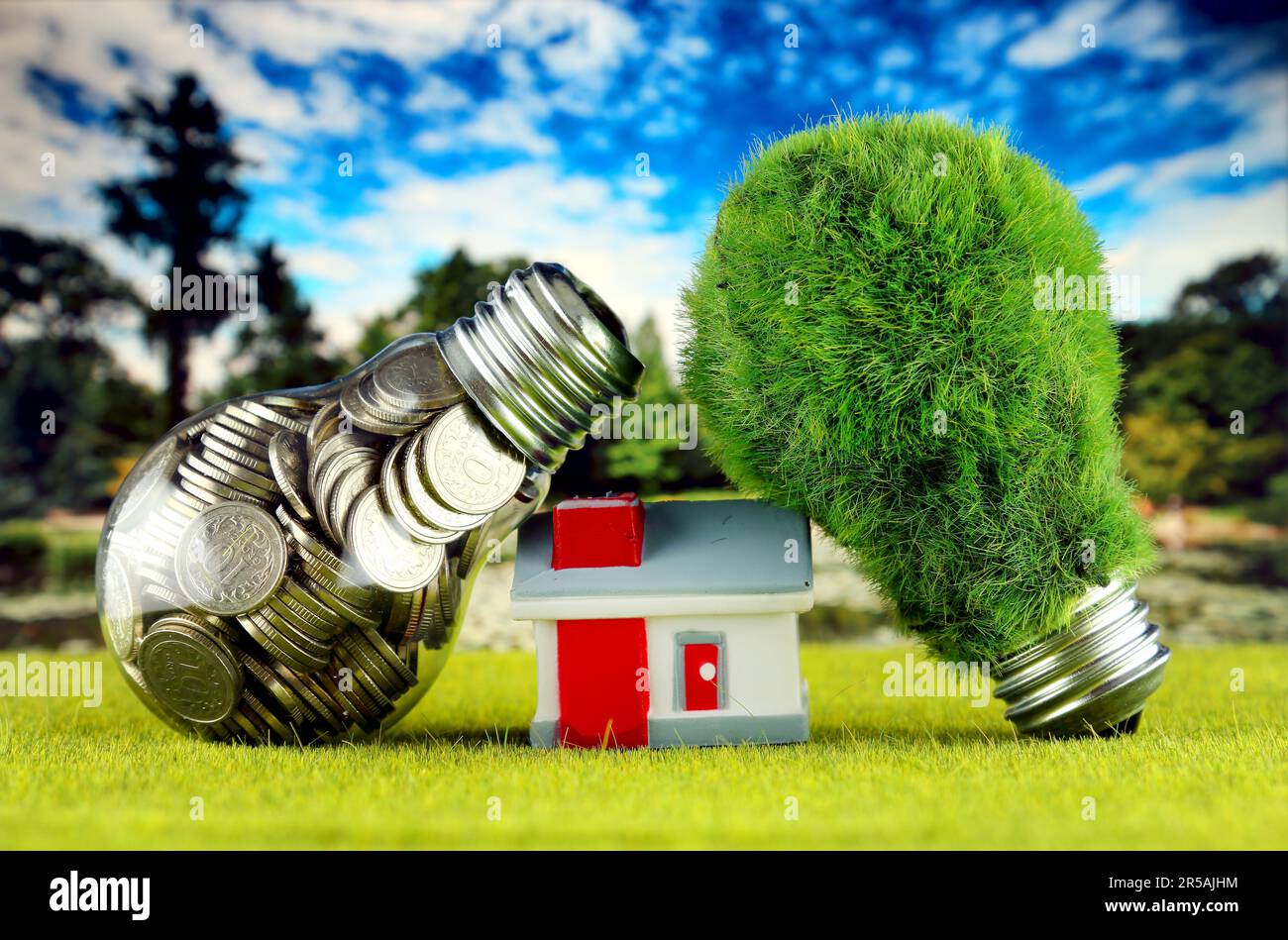 Monete all'interno della lampadina, lampadina verde eco con erba e casa in miniatura. Concetto di energia rinnovabile. I prezzi dell'elettricità, il risparmio energetico nelle ore Foto Stock