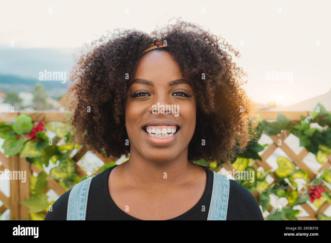 Felice giovane ragazza africana che ha divertimento sorridente di fronte alla macchina fotografica sul patio della casa Foto Stock